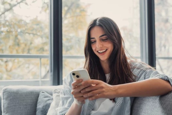 Pessoa sorrindo enquanto usa o celular